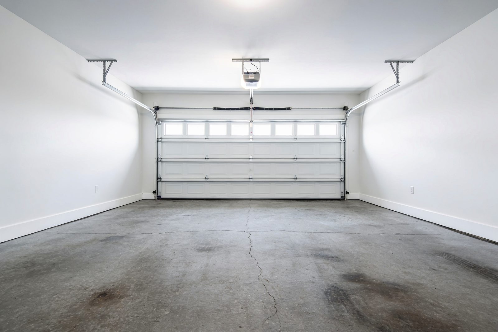Before: a bare garage slab with dull grey concrete, oil staining and a crack running across the floor.